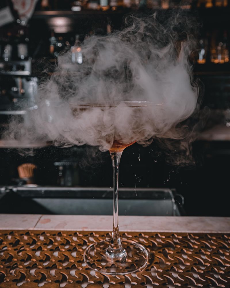 Smoky signature cocktail on a dimly lit bar counter