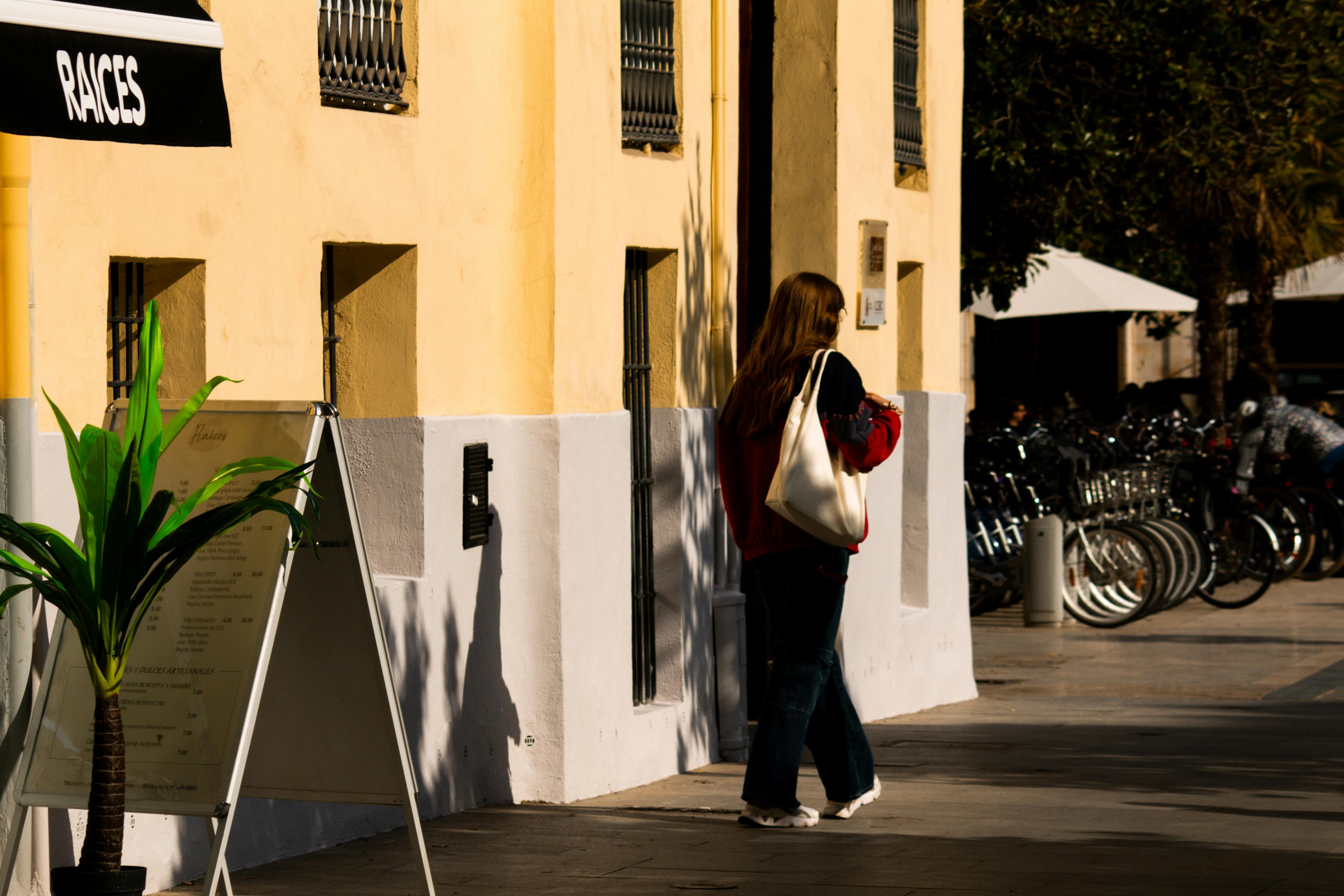 passerby in a red jacket walking in front of a yellow building