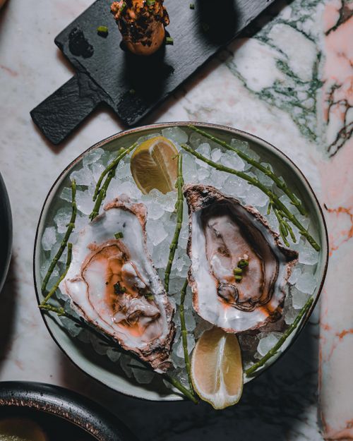 Free Close-up of fresh oysters on ice with lemon wedges and seaweed, perfect for gourmet dining themes. Stock Photo