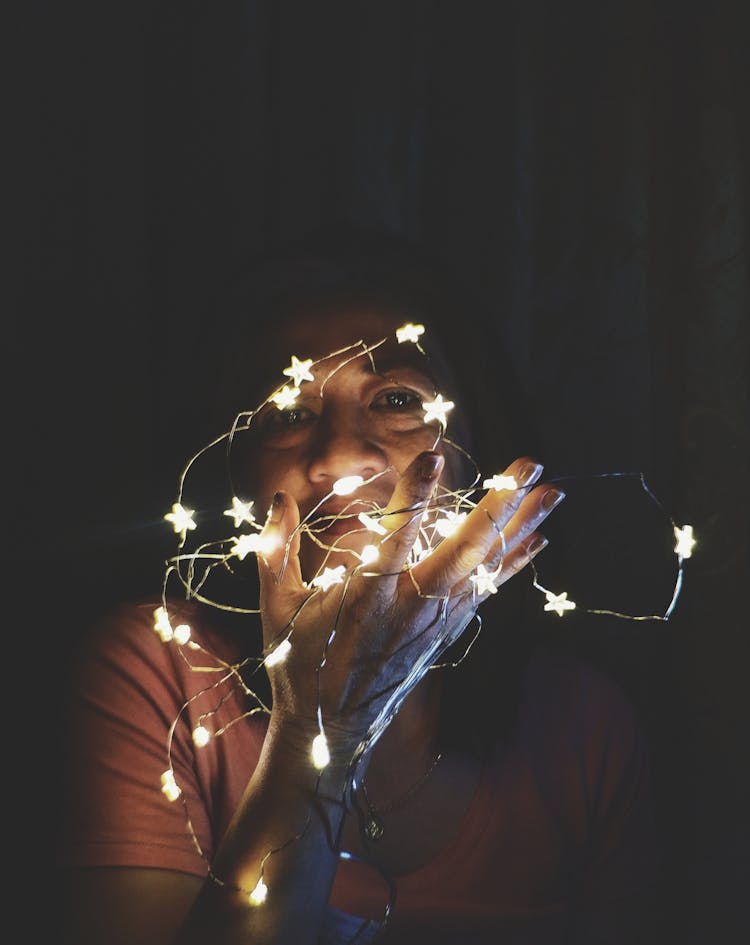 Close-Up Photo Of A Woman Holding String Lights