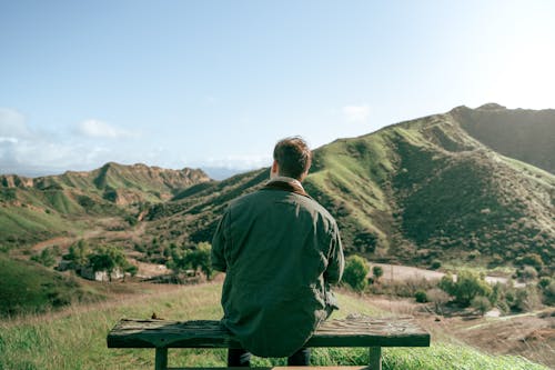 Man Sitting on a Bench Looking at Mountain Landscape