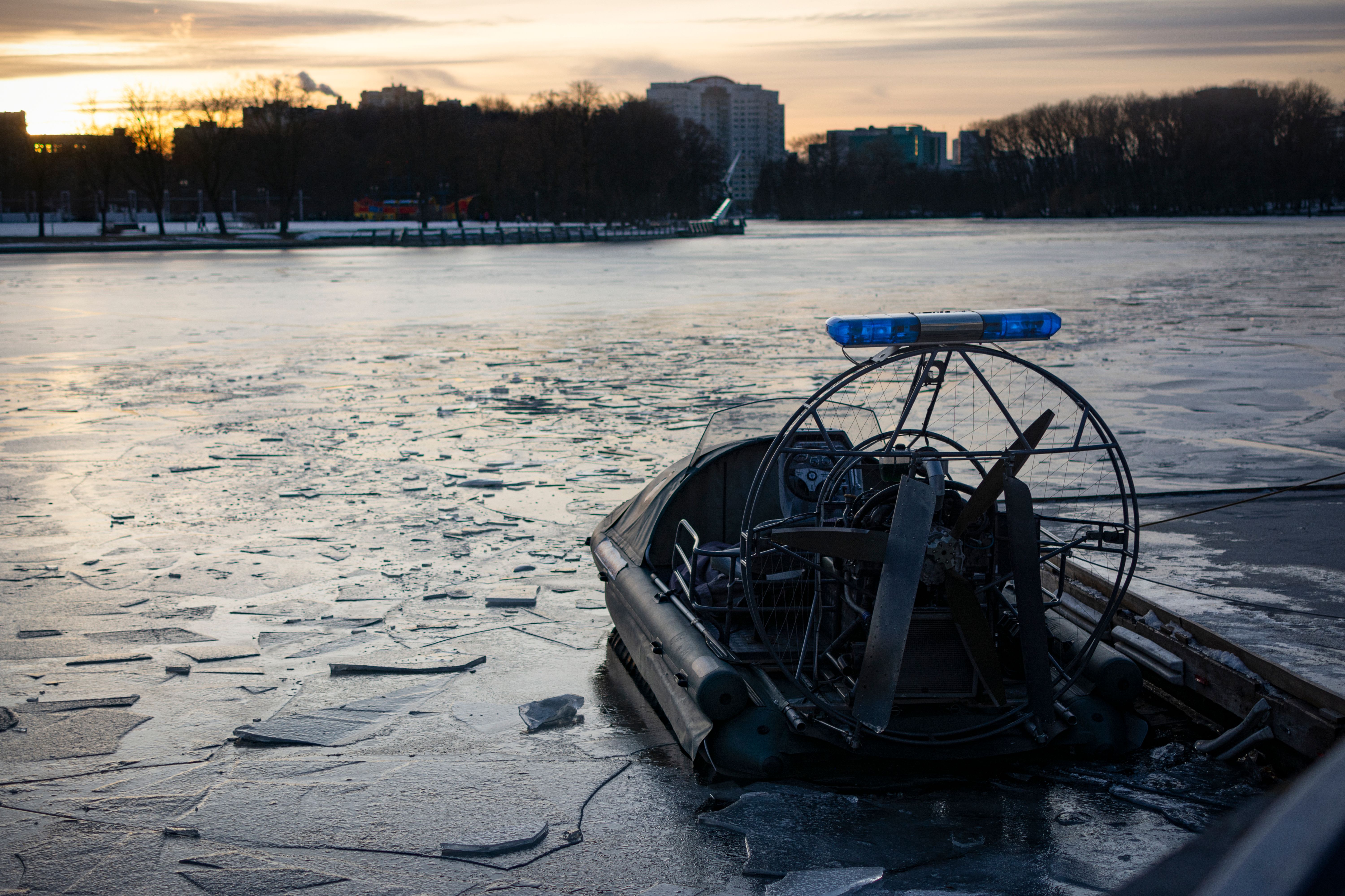 A frozen river scene in Minsk featuring an airboat at sunset, capturing the cold winter atmosphere.