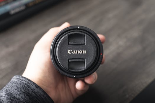 Hand holding a camera lens cap in Nueva York, highlighting photography equipment.
