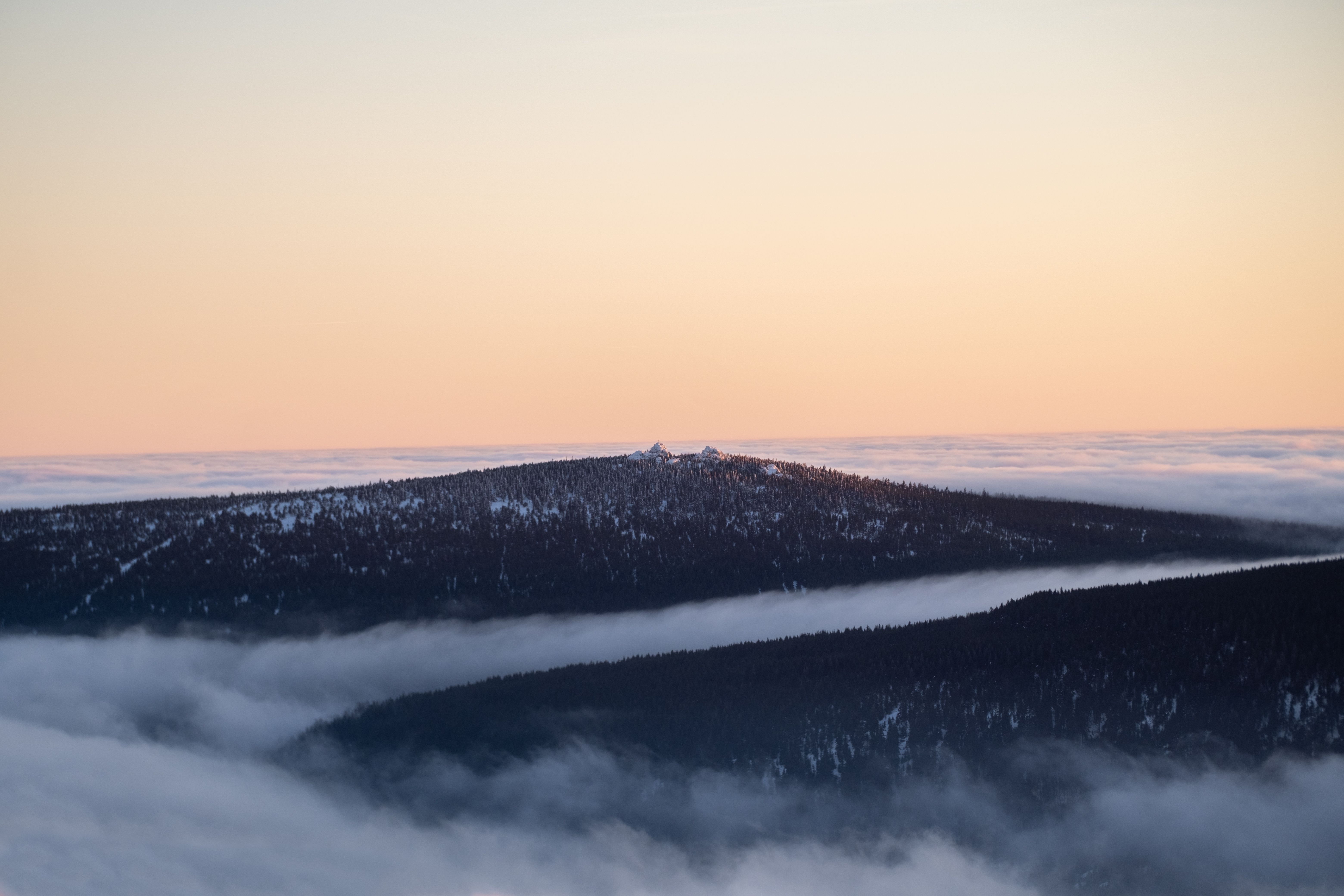 A serene winter landscape with snowcapped mountains surrounded by mist and soft sunrise colors.. pexels, serene, winter