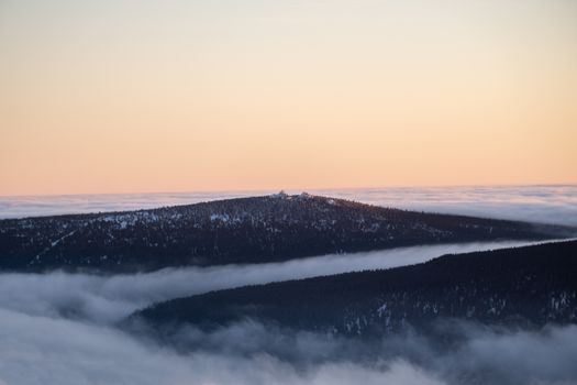 A serene winter landscape with snowcapped mountains surrounded by mist and soft sunrise colors.. pexels, serene, winter