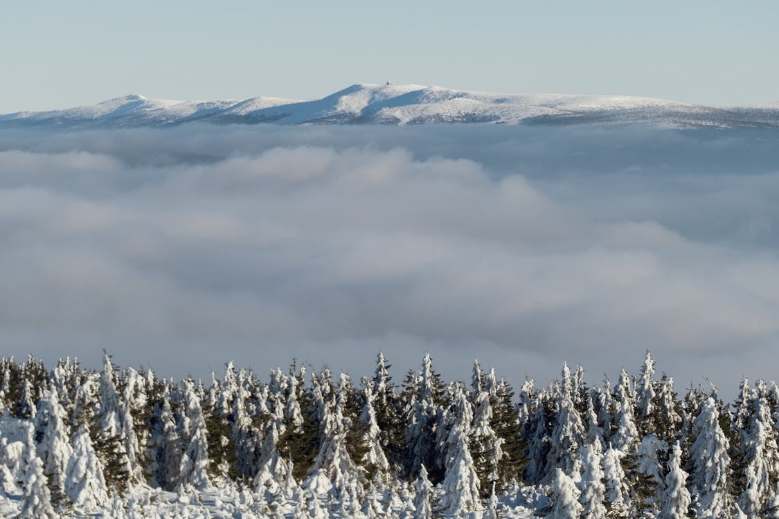 Snowcapped Mountains Above the Valley Covered with Clouds