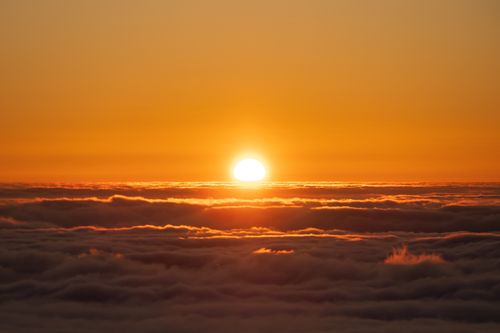 Free A breathtaking sunset over a sea of clouds with vivid orange hues lighting the sky. Stock Photo