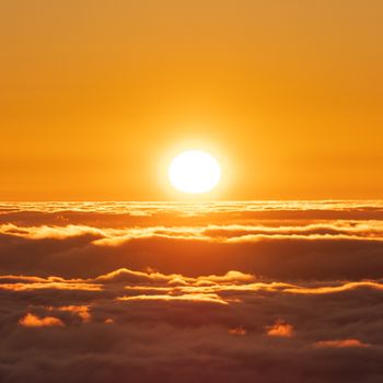 A stunning sunrise with golden tones illuminating the clouds below, creating a serene atmosphere.
