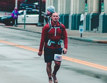 在西弗吉尼亚州惠灵，一位父亲背着孩子参加街头马拉松比赛