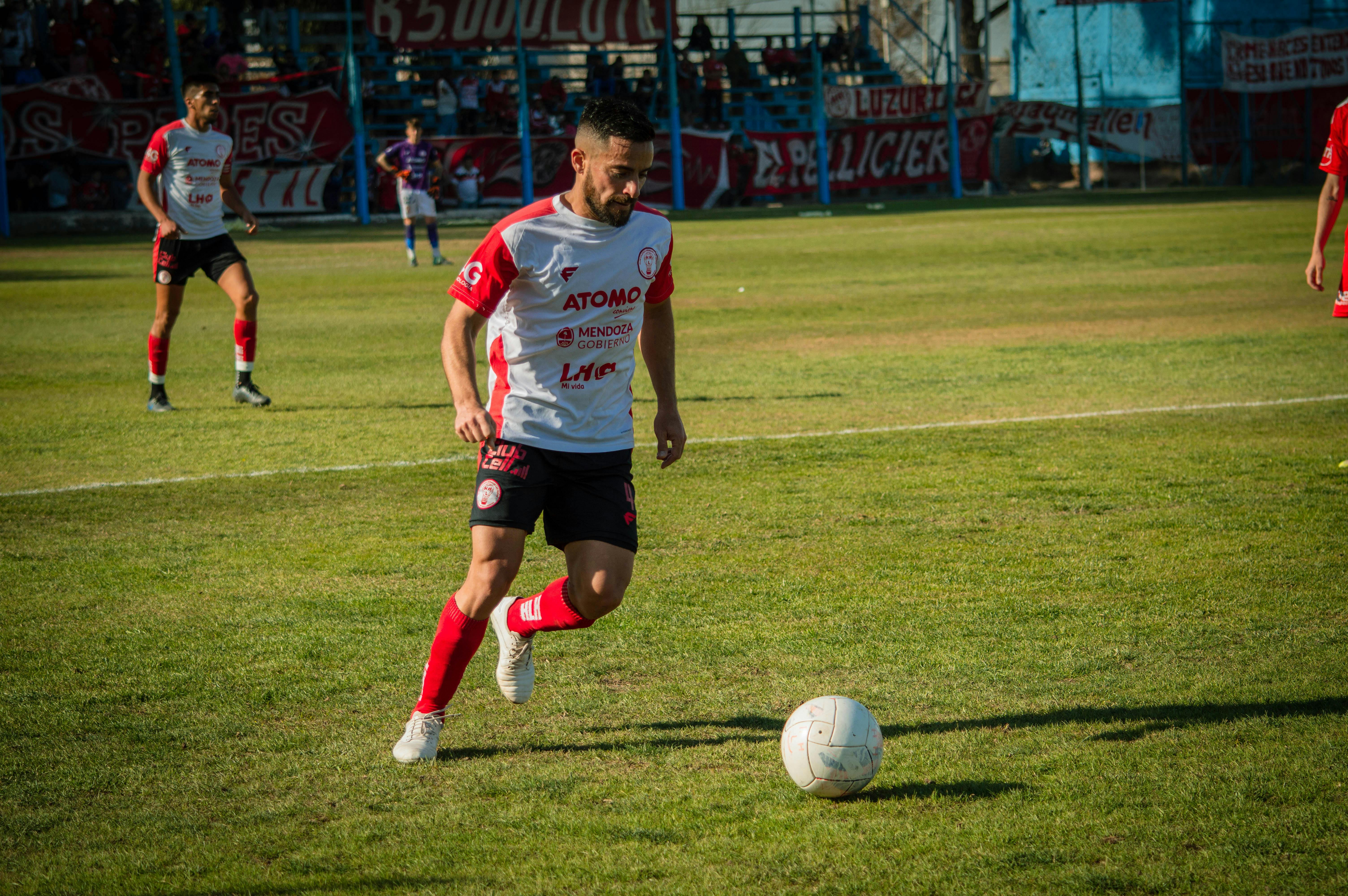 a soccer player in red and white is running after the ball