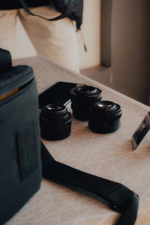 Camera Lenses and Smartphone Next to the Bag