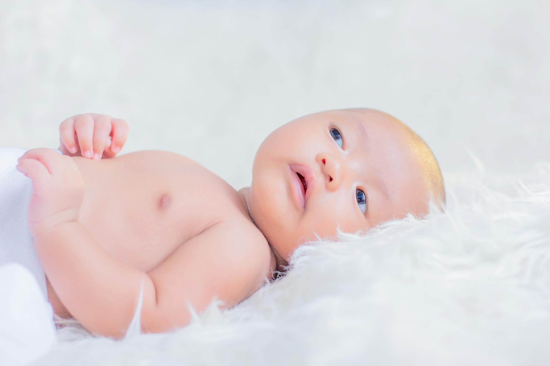 A cute newborn baby lying on a soft white blanket, radiating innocence and purity.