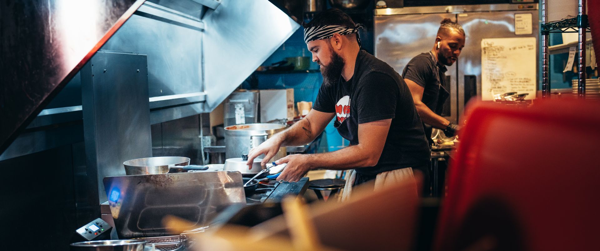 Two chefs work diligently in a bustling restaurant kitchen, preparing meals and managing dishes.
