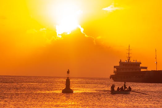 Dramatic ocean sunset with silhouetted ship and buoy, creating a vibrant orange sky and water reflection.