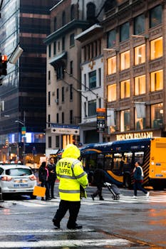 A New York traffic officer manages a busy city intersection on a rainy day.