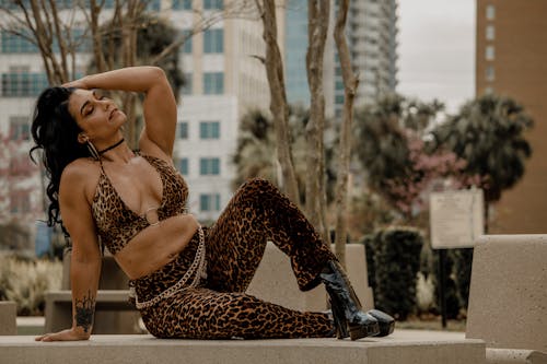 A woman in a leopard print outfit sitting on a ledge