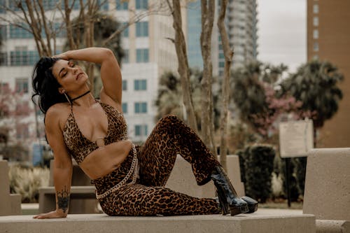 A woman in leopard print pants sitting on a ledge