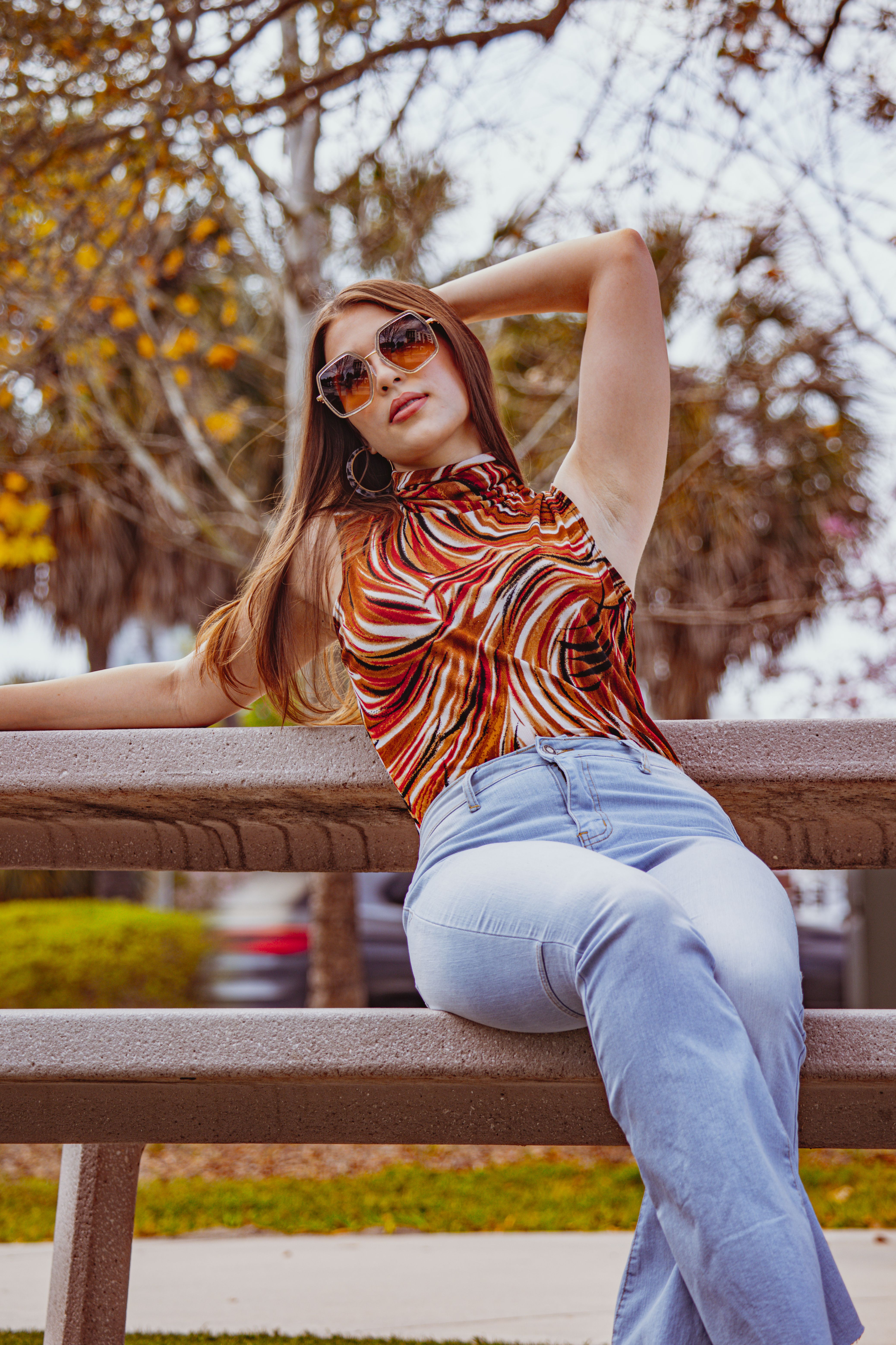A woman in jeans and a top sitting on a bench · Free Stock Photo