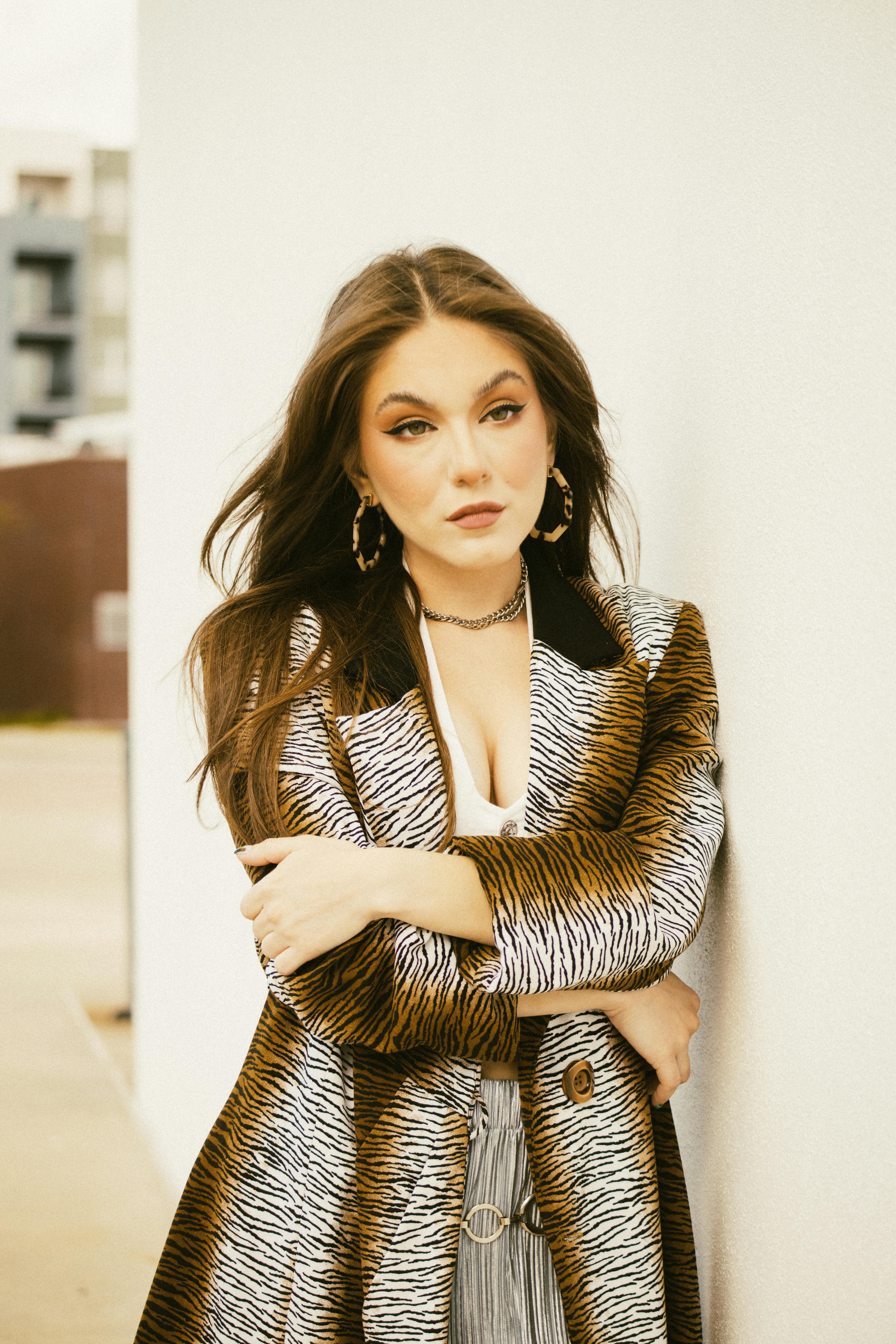 a woman in a coat leaning against a wall