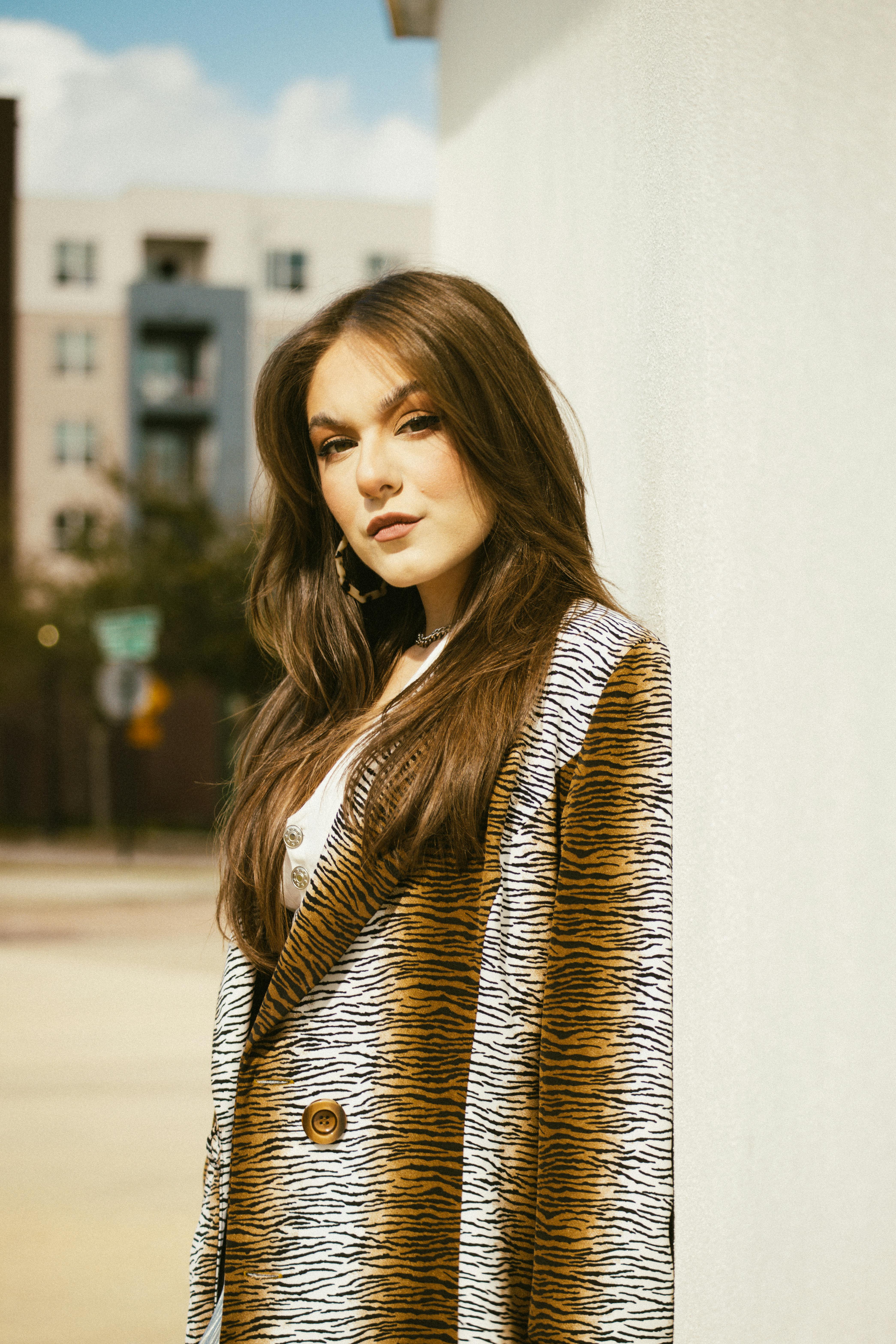 a woman in a coat leaning against a wall