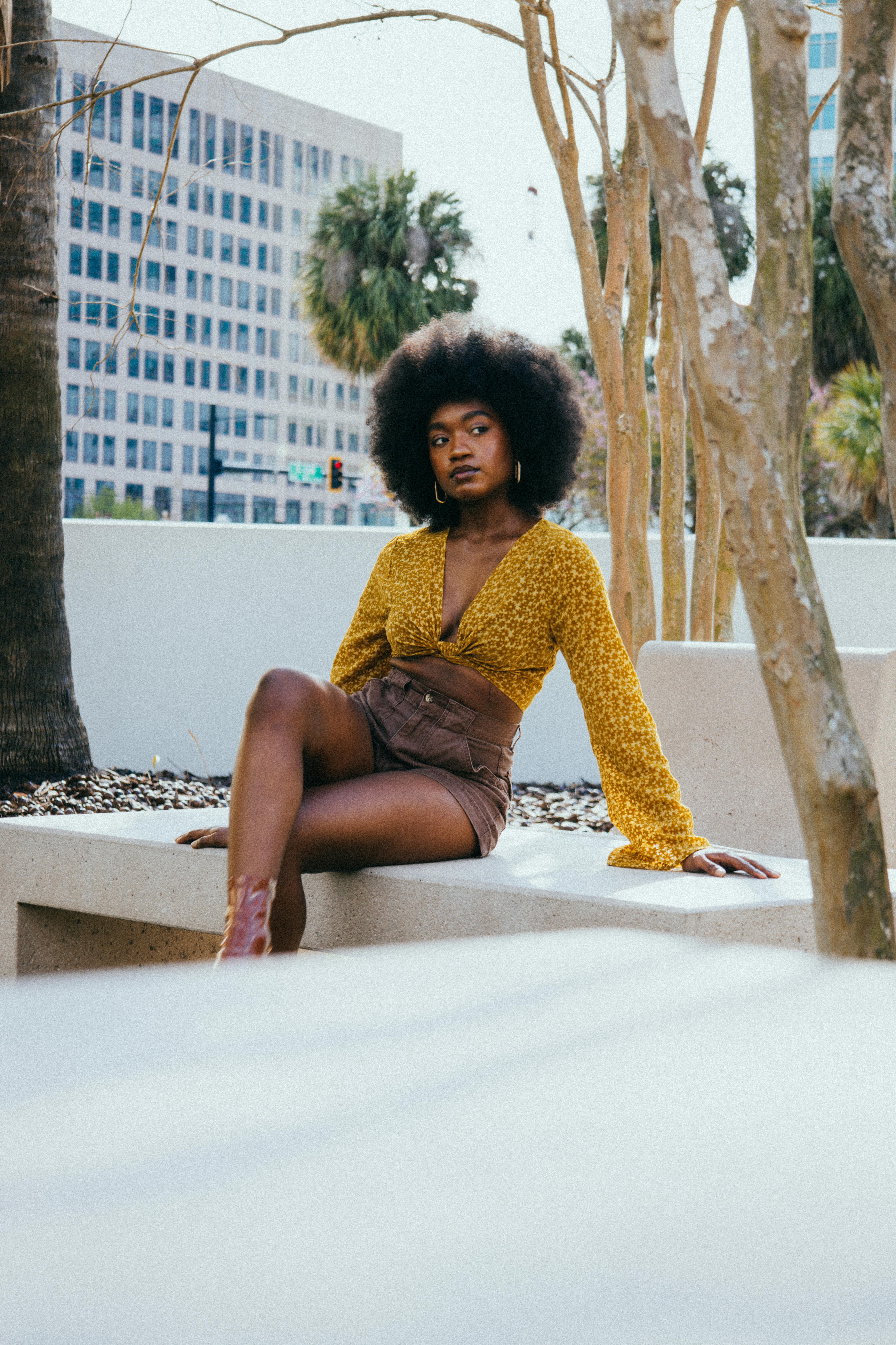 a woman with afro hair sitting on a bench