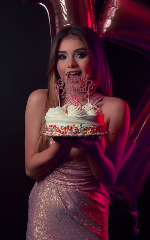 Free Young Woman in a Pink Dress Holding a Birthday Cake  Stock Photo