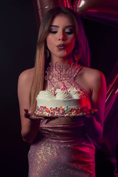 A young woman celebrates her birthday with a colorful cake and glam ambiance.