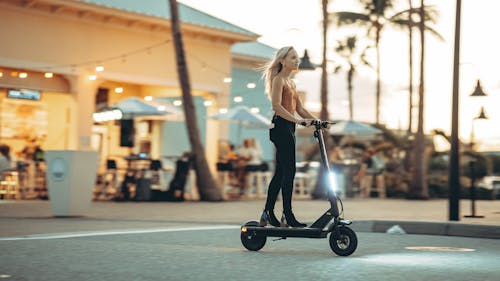 Woman Riding on a Scooter on a Street at Sunset 