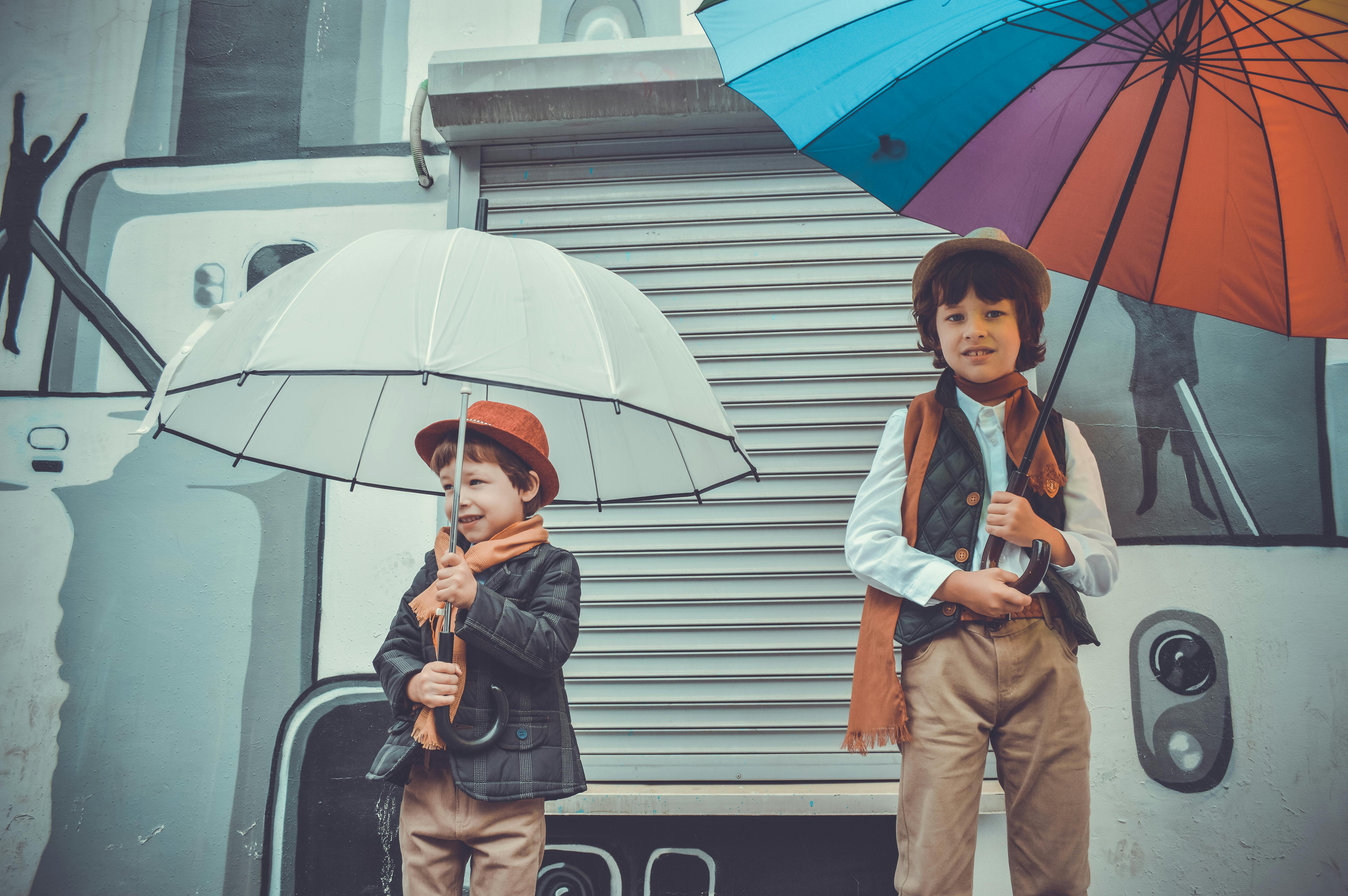 two children holding umbrellas while smiling