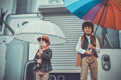 Двое детей держат зонтики, улыбаясь
