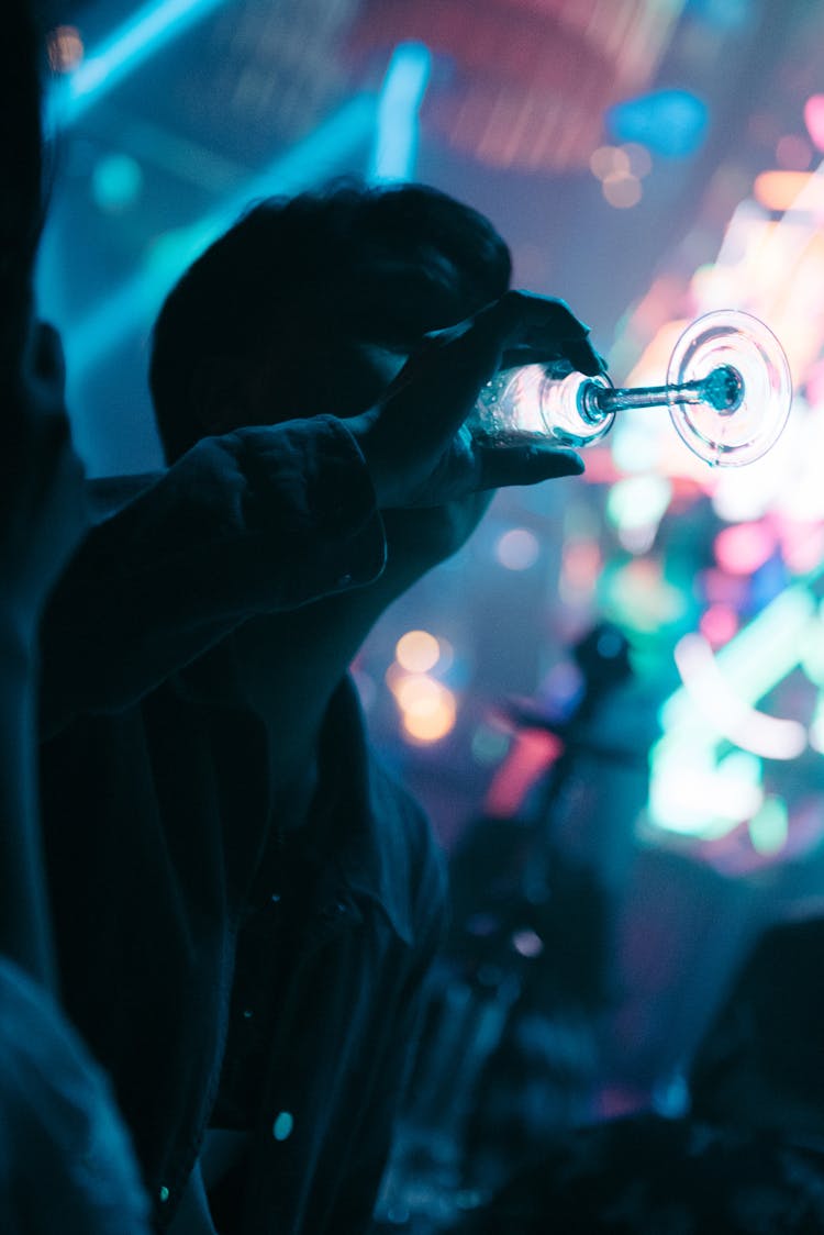 Man Drinking From Glass In Nightclub