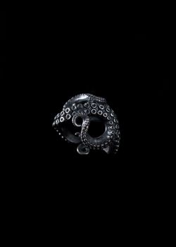 Close-up of a handmade octopus tentacle ring against a black backdrop.