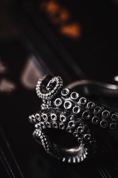 Intricate silver octopus tentacle ring against a dark background, emphasizing detailed craftsmanship.
