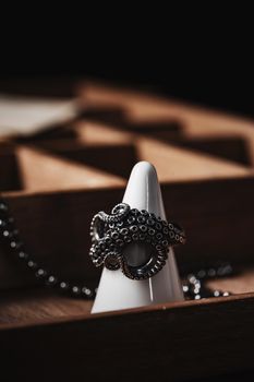 Silver octopus-shaped ring elegantly displayed on a white jewelry stand with a wooden background.