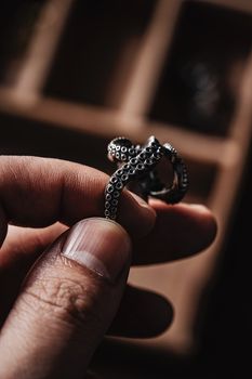 Close-up of a hand holding a detailed octopus tentacle ring, showcasing artistry in jewelry design.