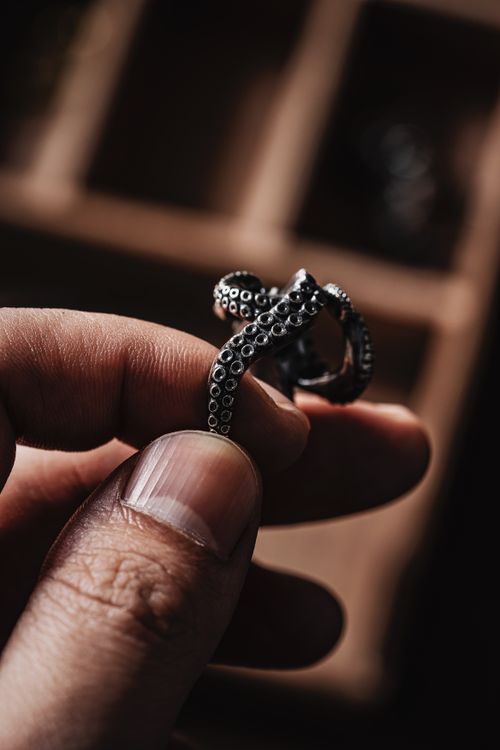 Free Close-up of a hand holding a detailed octopus tentacle ring, showcasing artistry in jewelry design. Stock Photo