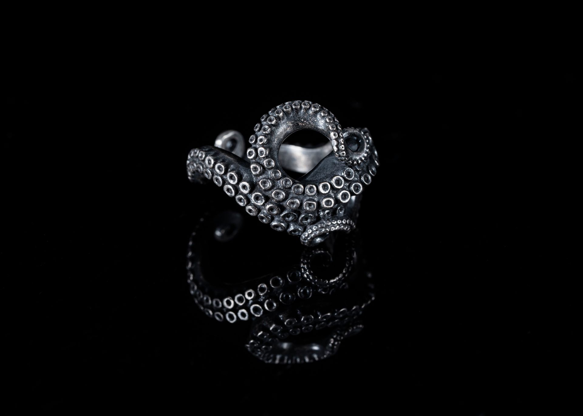 Artistic silver tentacle ring with dark oxidized finish, studio shot on black.