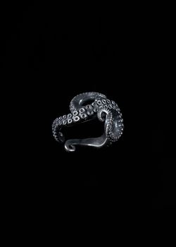 Detailed closeup of a silver ring mimicking an octopus tentacle, against a black background.
