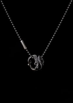 Silver octopus pendant necklace with intricate tentacle design on dark background.