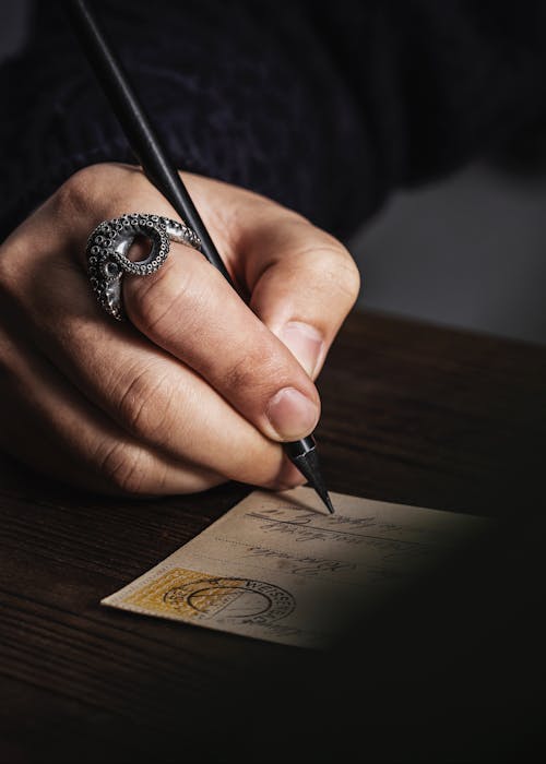 Closeup of a Hand Wearing a Ring, Writing a Postcard