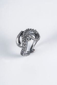Close-up of a detailed silver octopus tentacle ring on a white background.