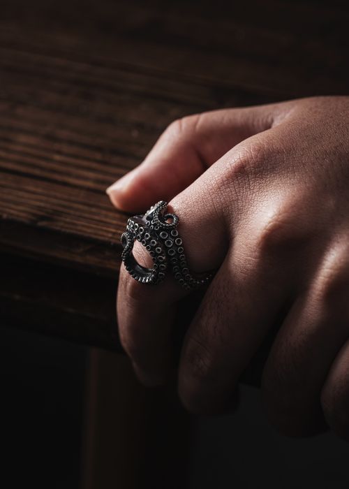 Free A detailed close-up of a hand wearing an octopus-themed ring, shot in a moody setting. Stock Photo