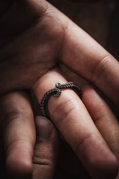 Close-up of an oxidized silver octopus tentacle ring on finger, showcasing intricate tentacle design.