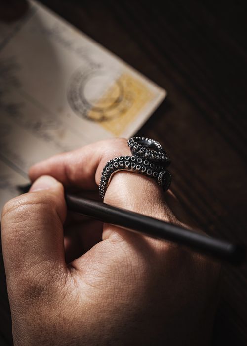 Free Close-up of hand holding pen, writing on paper, octopus tentacle ring. Stock Photo
