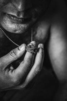 Black and white portrait of a man examining a detailed octopus pendant.