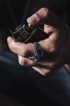 Close-up of a hand holding a lighter, adorned with a unique octopus tentacle ring.