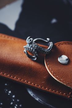 Close-up of an octopus-shaped ring resting on a leather sheath.