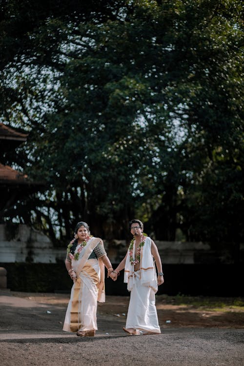 Couple in Traditional Clothing Holding Hands and Walking