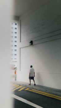 A man walks in an urban Singapore tunnel under soft daylight.
