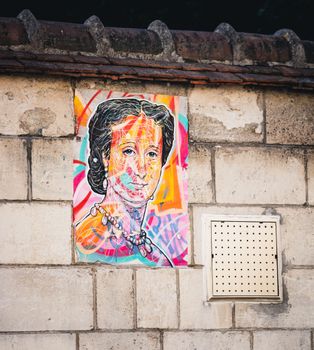 Colorful street art portrait of a woman painted on a brick wall, showcasing creative expression.